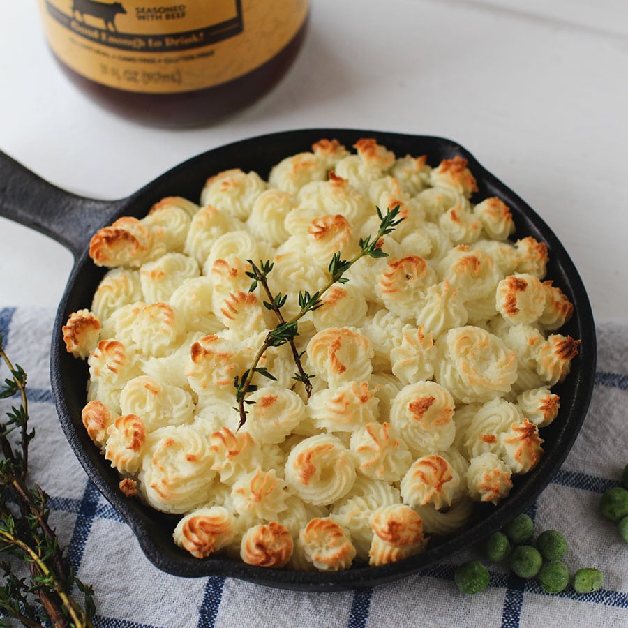 mini shepards pies in cast iron pan on kitchen counter with zoup beef bone broth jar in background